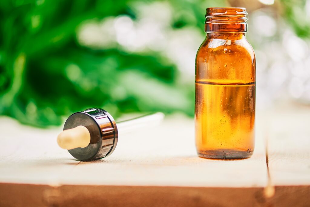 CBD hemp oil, droplet dosing a ecological hemp plant herbal pharmaceutical cbd oil from a jar.